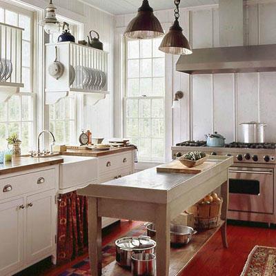 रोशनी and bright airy kitchen with windows along the left side, over the sink area and in the middle of the kitchen, a long prep table with room for storage underneath. Also a stainless steel gas/oven range is a the far end of the kitchen.