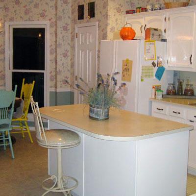 vanhentunut kitchen with a white kitchen island and a bar stool pulled up to it 