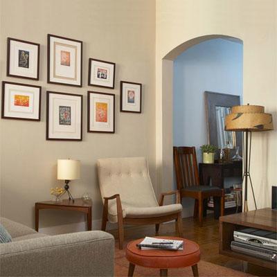 जीवित room with mid-century furniture, lamps and arm chair with framed art on the light cream walls