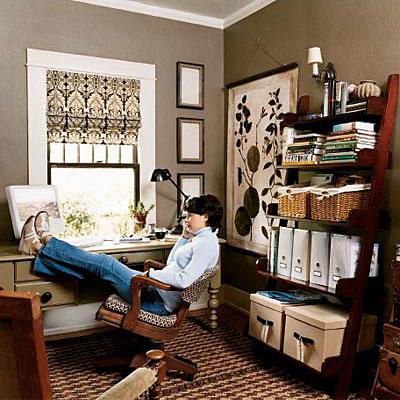 ए desk is positioned in front of the window in this home office, while ladder shelving with decorative storage containers are organized on the opposite wall. Chocolate brown walls and black, brown and cream window treatment completes the look of this work
