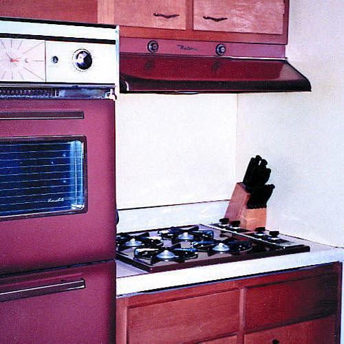 रगड़ा हुआ kitchen cabinets with an old oven and stove in burgundy colors