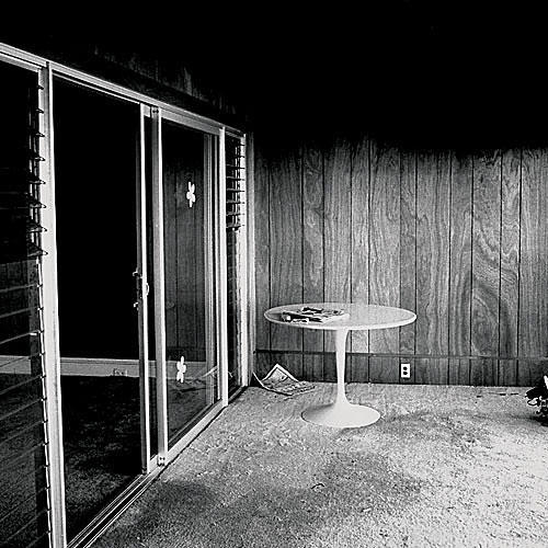 puu paneling in a carpeted room with a round white table and a sliding glass door to the left side 