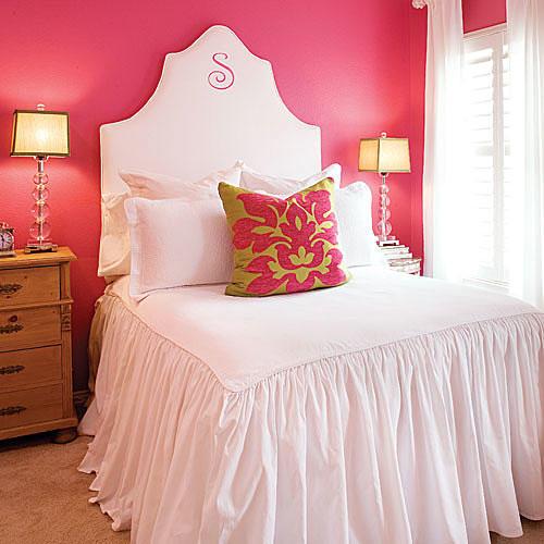 उज्ज्वल pink-coral paint on the wall off-sets a white, fabric headboard with a gathered comforter on the bed giving a tropical feel to the decor