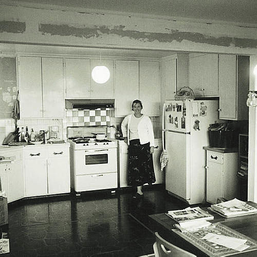 vanhentunut kitchen with plain white cabinets, dark floors and an old white stove