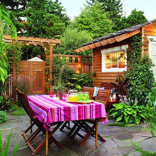 उज्ज्वल and colorful backyard with a striped tablecloth over an outdoor table with a wooden garden shed, in the background