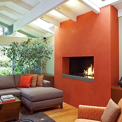 ए vibrant tomato bisque-hued plaster added to this fireplace remodel turned the hearth into a modern showpiece in this living room.