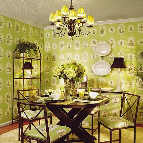 बाद photo with a dining room that’s wallpapered in pale, green Asian designs, and a dark wood dining room table in the middle of the room set with china (and chairs surrounding it). 