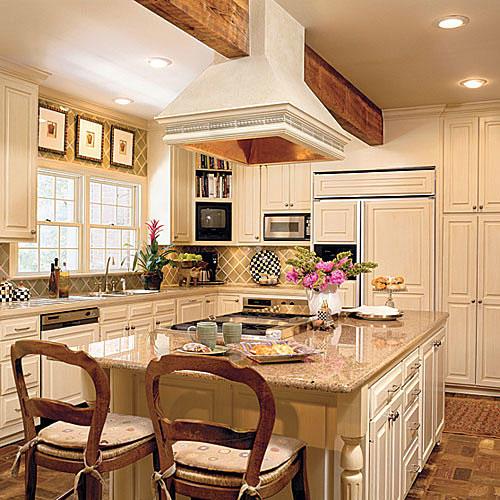 मलाईदार kitchen cabinets that also covered the front of the refrigerator, dish washer, and a granite kitchen island countertop and copper-lined stove hood above the island