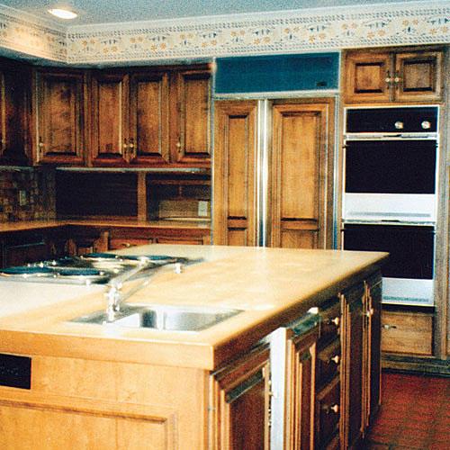 बड़े kitchen island with brown cabinets with an old oven and old florescent lighting in the ceiling