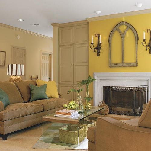 पीला walls highlight the artwork above the family room fireplace while the couch faces a clear, glass, mod coffee table