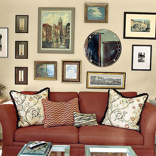 परिवार room wall with gallery layout of framed prints, paintings and mirrors hung over a red couch with pillows