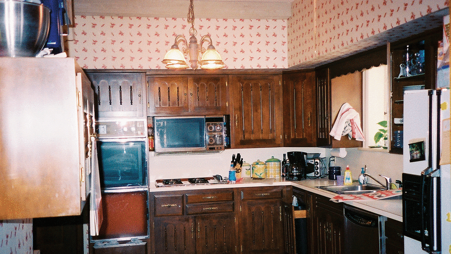 रगड़ा हुआ kitchen with dark wooden cabinets, red tile floors and old kitchen appliances