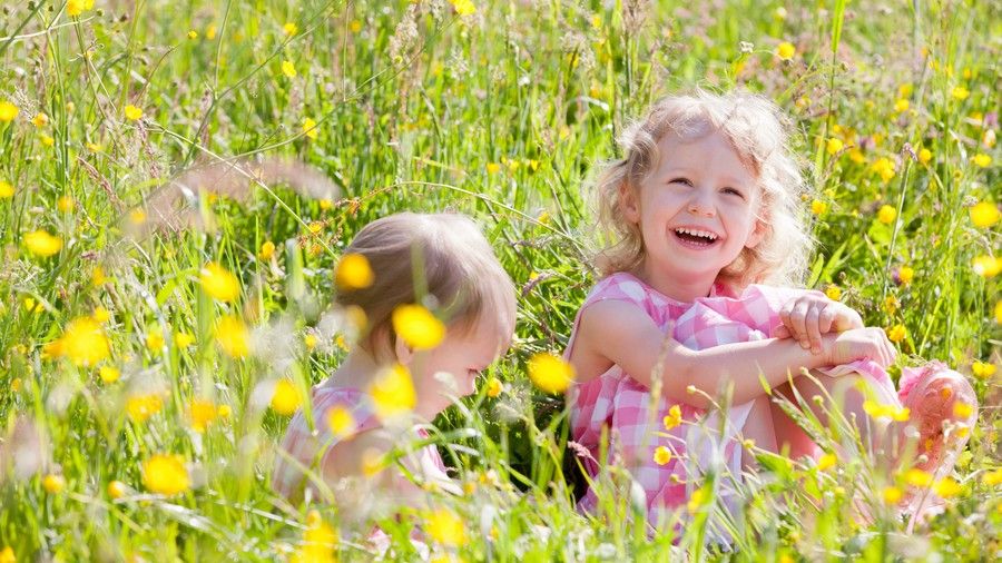 बच्चा girls playing in flower field